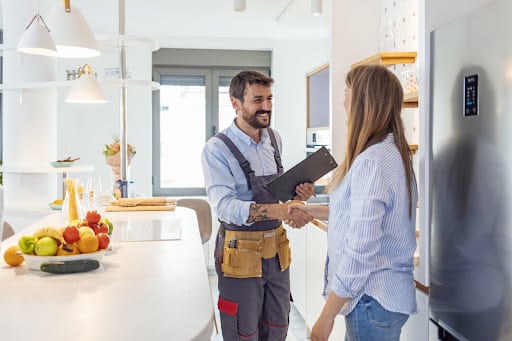 plumber-repairs Plumber shaking hands with customer inside kitchen.