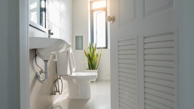 White toilet in bathroom with sink and window