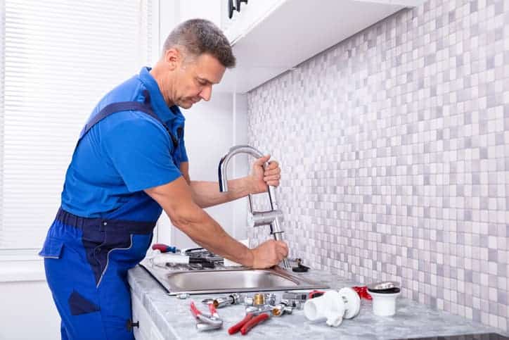 Plumber working on kitchen faucet
