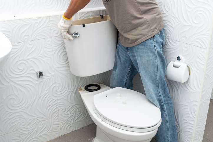 man removing toilet tank