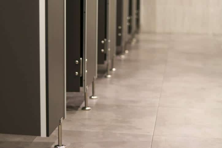 the bottom of multiple bathroom stalls in a public restroom