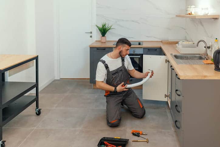 A plumber fixing a kitchen sink in a new home.