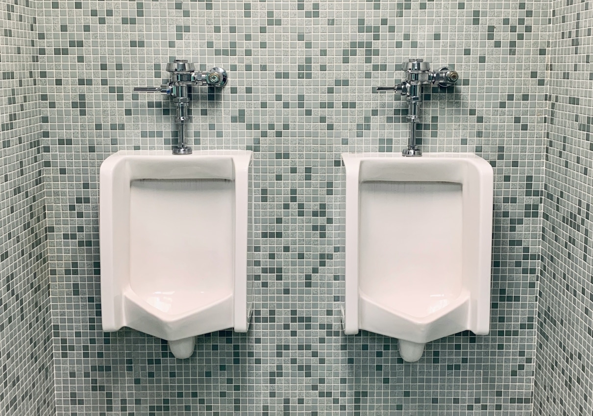 two urinals in bathroom on tiled wall
